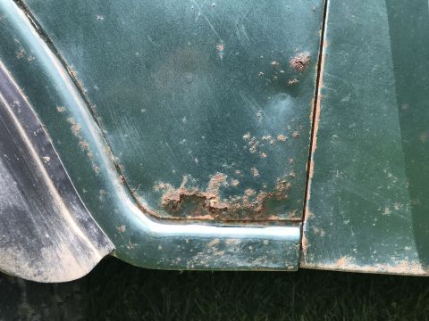 1979 Jeep CJ5 - Close-up of a green vehicle's body panel shows extensive rust and corrosion.