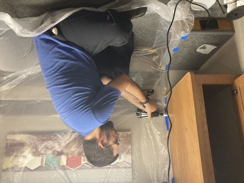 2015 Ford F-550 - A person is using a drill to work on the interior cabinetry of a recreational vehicle.