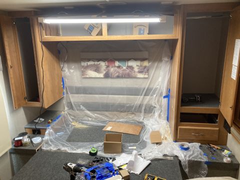 2015 Ford F-550 - Interior scene of an RV bedroom, covered in plastic sheeting and surrounded by tools and supplies, suggesting ongoing renovation work.