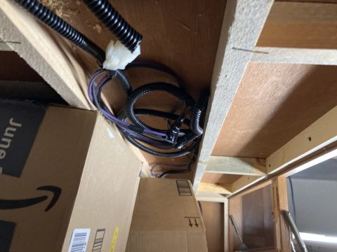 2015 Ford F-550 - A view of a wiring harness and cardboard boxes stored beneath a wooden structure, with a Supermotors.net watermark visible.