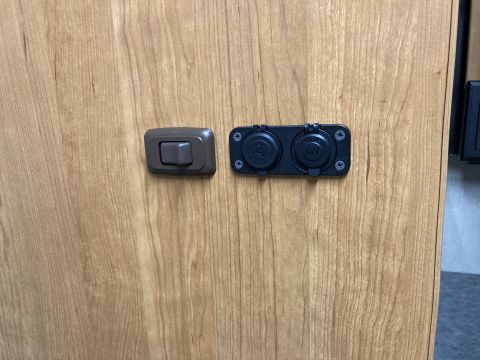 2015 Ford F-550 - Interior panel shows a light switch and two power outlets mounted on a wood-grain surface.