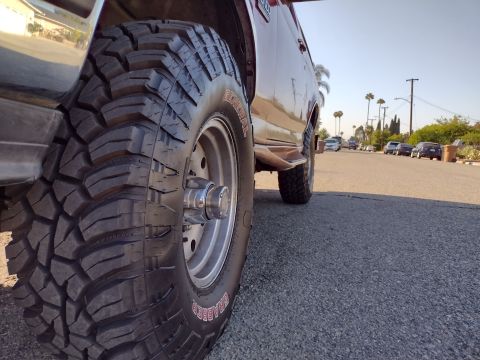 1994 Ford Bronco - Close-up of a 1994 Ford Bronco's large off-road tire and side panel.