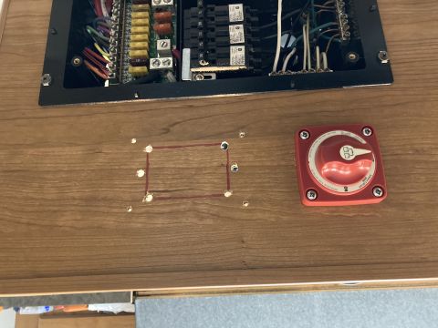 2015 Ford F-550 - Close-up of an electrical panel and a red battery disconnect switch mounted on a wood-grain surface.