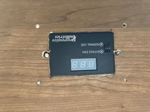 2015 Ford F-550 - A close-up of a Progressive Industries EMS-HW30C surge protector mounted on a wood-grain surface.