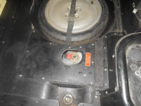 1992 Ford Bronco - Spare tire well showing the fuel pump access panel and a warning label. The image is from Supermotors.net.