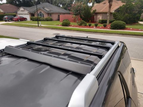 2018 Toyota 4Runner - Aftermarket roof rack installed on a dark SUV, with houses in the background.
