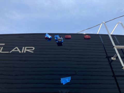 2015 Ford F-550 - The rear of a black RV, possibly a Flair model, is shown with three red lights and two small blue objects secured with tape.