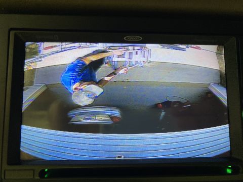 2015 Ford F-550 - A person is seen working on the trunk of a car, as viewed from a backup camera.