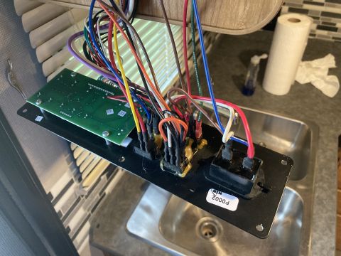 2015 Ford F-550 - An electronic control panel with numerous wires is shown, possibly for an RV or similar vehicle, above a stainless steel sink.