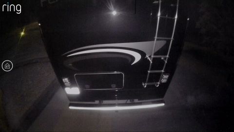 2015 Ford F-550 - The rear of a black RV is visible at night, showing a ladder and reflective tape on the bumper.