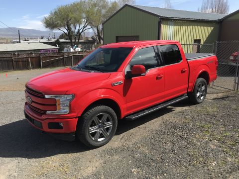 2018 Ford F-150 - A red 2018 Ford F-150 pickup truck is parked outdoors on a gravel lot next to a building.