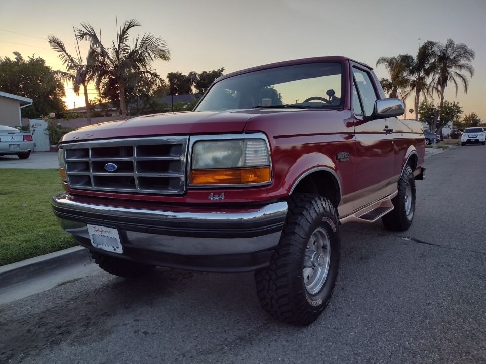 Red 1994 Ford Bronco 4x4 parked curbside at sunset