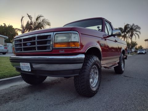 1994 Ford Bronco - Red 1994 Ford Bronco with aftermarket wheels and tires parked on a residential street.