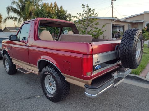 1994 Ford Bronco - This red Ford Bronco features tan two-tone paint and a rear-mounted spare tire.