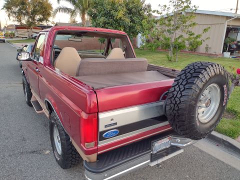 1994 Ford Bronco - This red Ford Bronco is shown from the rear, with its removable top off and a spare tire mounted on the back.