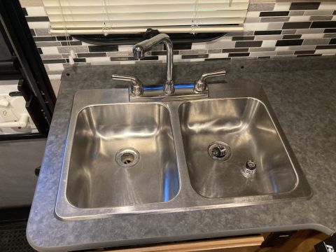 2015 Ford F-550 - A close-up view of a double basin sink with a modern faucet and a mosaic tile backsplash.