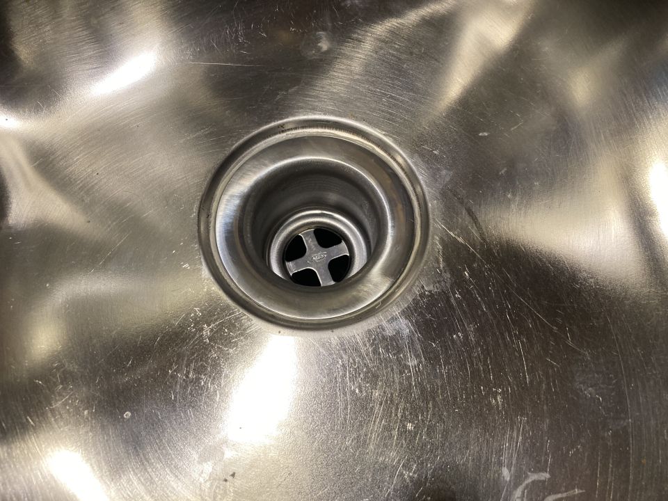 Close-up of a stainless steel sink drain with a cross-shaped strainer