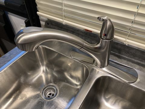 2015 Ford F-550 - A brushed nickel kitchen faucet with a pull-down sprayer is mounted over a stainless steel double sink.