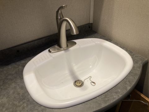 2015 Ford F-550 - A close-up view of a bathroom sink and faucet, a metal chain stopper in the drain.