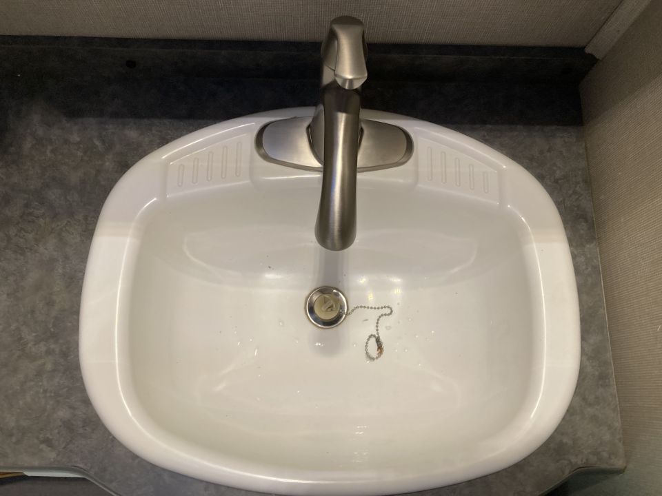White bathroom sink with a brushed nickel faucet and a drain chain