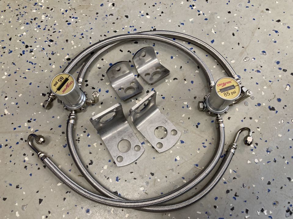 Brake line kit with two braided hoses, two pressure regulators marked 85 psi, and four mounting brackets