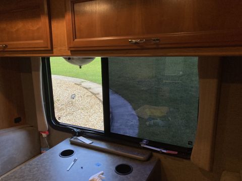 2015 Ford F-550 - View from inside an RV, looking out a window at a lawn and gravel path.