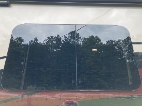 2015 Ford F-550 - A tinted window on an RV reflects trees and the sky, with a Supermotors logo visible at the bottom.