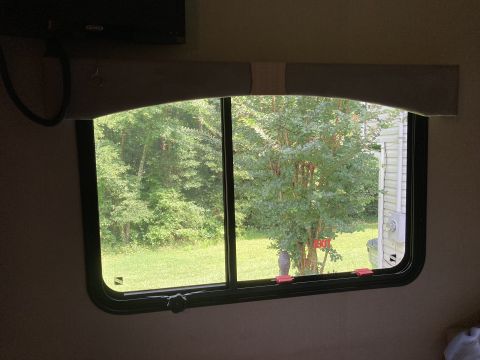 2015 Ford F-550 - View from inside an RV, looking out a window at a grassy yard and trees. The Supermotors.net logo is in the lower right corner.