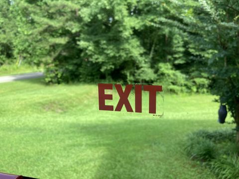 2015 Ford F-550 - Red EXIT sign on glass with a blurred outdoor scene behind it.