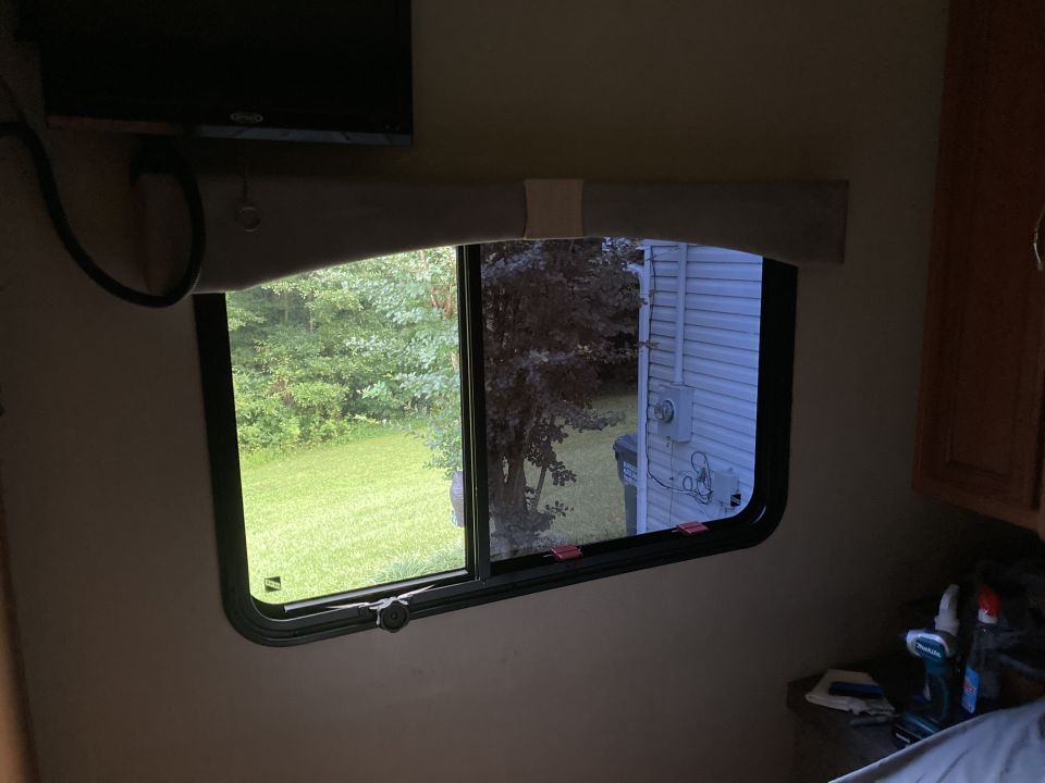 Interior view from a vehicle window showing a grassy yard and a house exterior