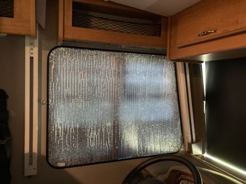 2015 Ford F-550 - Reflective window covering installed inside a vehicle, with visible wooden cabinetry and a partial view of the steering wheel.