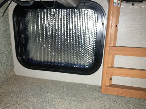 2015 Ford F-550 - Reflective insulation covers the interior of an RV window, adjacent to wooden paneling.