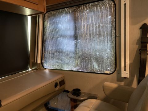 2015 Ford F-550 - Interior view of an RV window with a sunshade, showing a seat and part of the dashboard area.