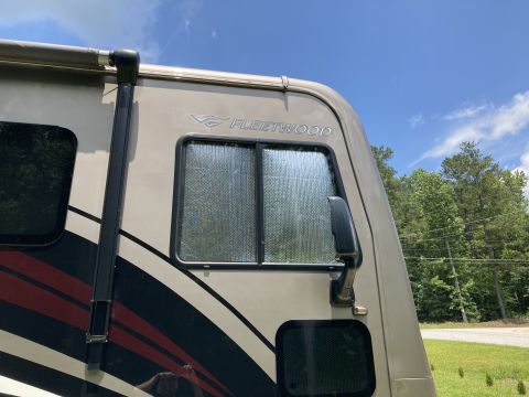 2015 Ford F-550 - A motorhome is seen from the side, displaying its Fleetwood branding and tan exterior paint.