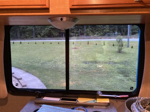 2015 Ford F-550 - Looking out from inside an RV, a grassy area with small trees and a road is visible through the window.