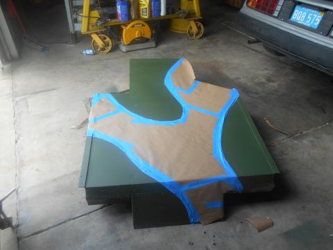 1992 Ford Bronco - A green metal part, possibly a body panel, is covered with masking tape in a workshop setting.