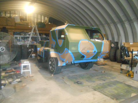 1992 Ford Bronco - A custom vehicle is being painted with camouflage in a garage, with blue and tan tape applied to sections of the body.