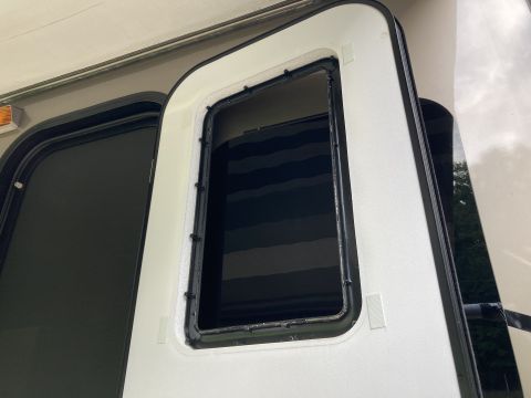 2015 Ford F-550 - The frame around an RV door window is shown, with the dark interior of the window visible.