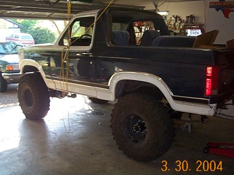 1986 Ford Bronco - A modified Ford Bronco sits in a garage, possibly undergoing repairs or upgrades.