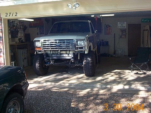 1986 Ford Bronco - This lifted truck, likely from the 1980s, is parked inside a garage with its front bumper removed.