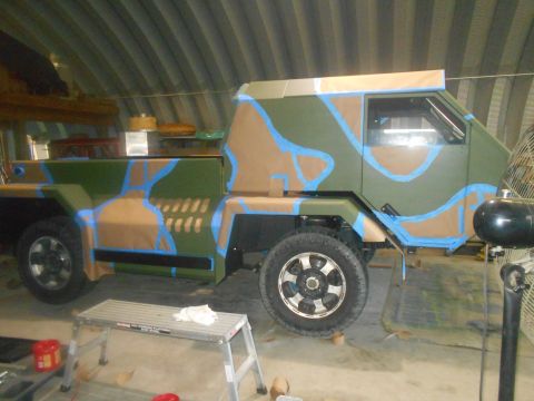 1992 Ford Bronco - A custom truck is undergoing a camouflage paint job in a workshop setting.