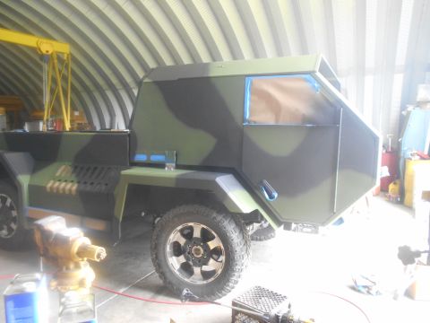 1992 Ford Bronco - A custom-built truck with a unique, angular body and camouflage paint scheme is shown in a workshop.