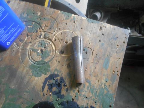 1992 Ford Bronco - A split metal part rests on a weathered wooden surface, next to a blue bottle.