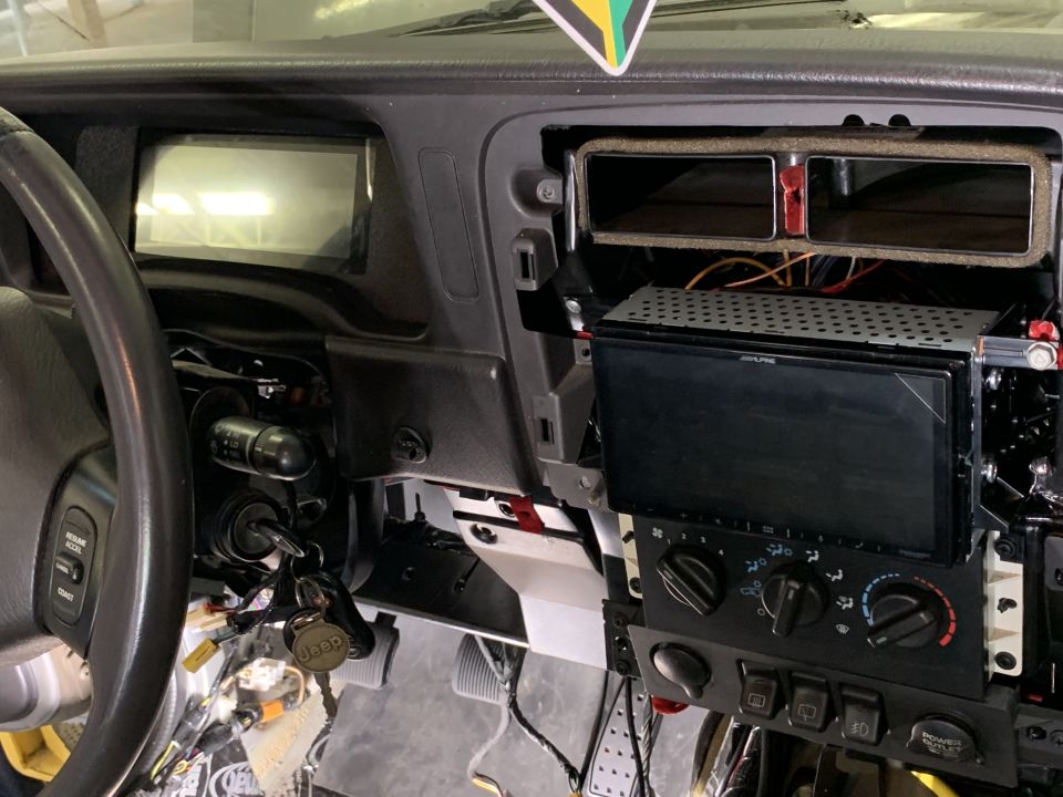 Jeep Cherokee interior showing steering wheel, dashboard with aftermarket stereo, and exposed wiring