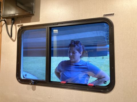 2015 Ford F-550 - A woman stands inside an RV, looking out a window at the grassy exterior.