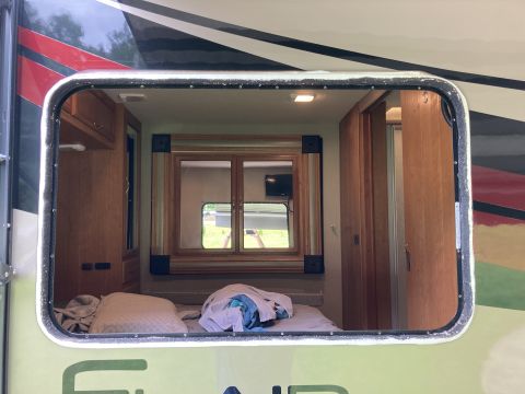 2015 Ford F-550 - View from outside into the interior of a camper van, showing the sleeping area and cabinetry.