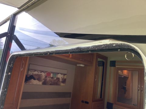 2015 Ford F-550 - Close-up of an RV window frame, revealing the interior with cabinetry and artwork.