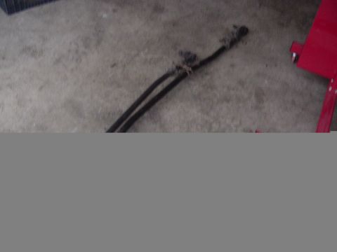 1987 Ford Bronco - Two black hoses are tied together on a concrete floor, with a red object visible to the right.