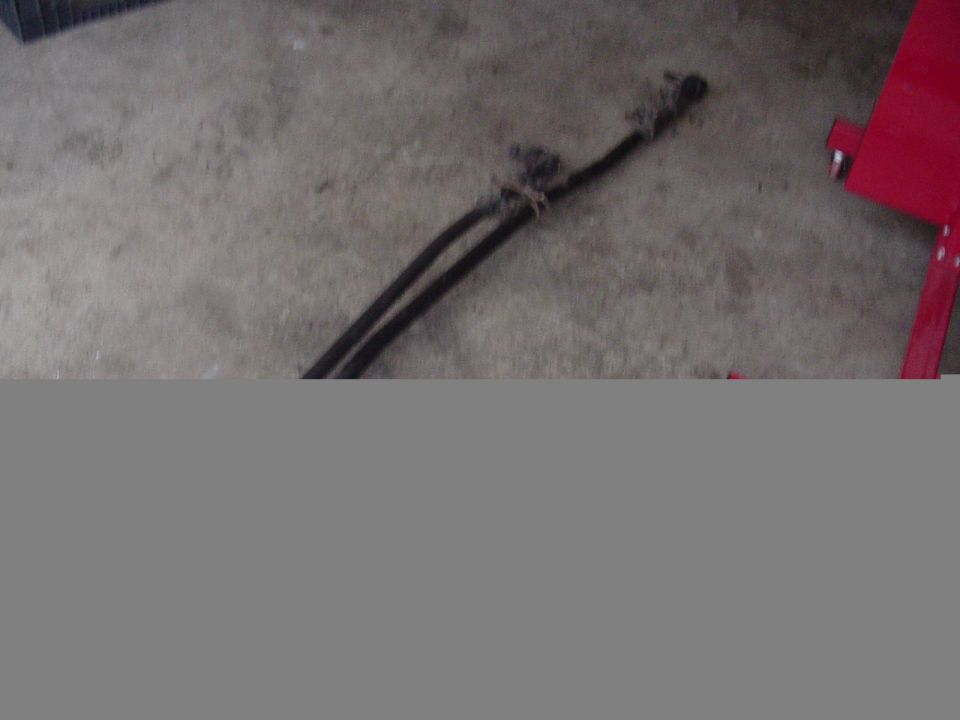 Two black hoses bound with wire on a concrete floor