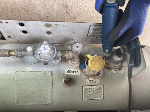 2015 Ford F-550 - Detail of a propane tank's fill and vapor connections, with a tool being used on one of the fittings.